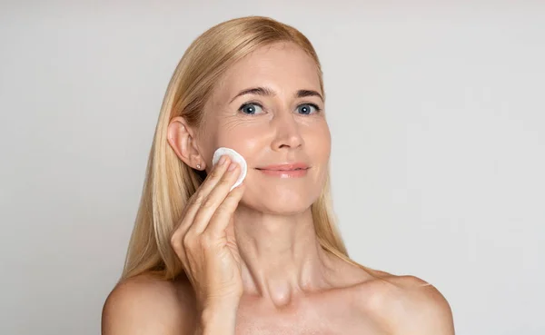 Remove makeup. Positive middle-aged woman with cotton pad — Stock Photo, Image
