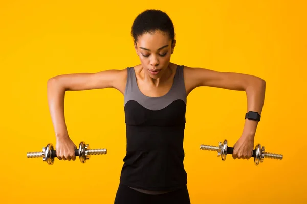 Sportig afro kvinna tränar med hantlar över gul bakgrund — Stockfoto