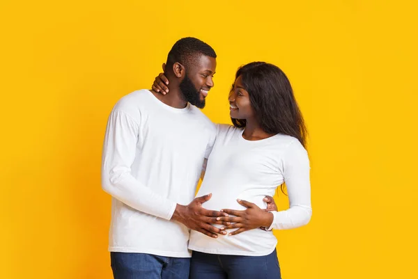 Веселая афро-беременная пара разговаривает на жёлтом фоне — стоковое фото