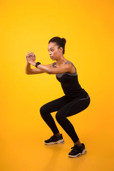 Afro-americano donna fare profondo squat esercizio su giallo sfondo — Foto Stock