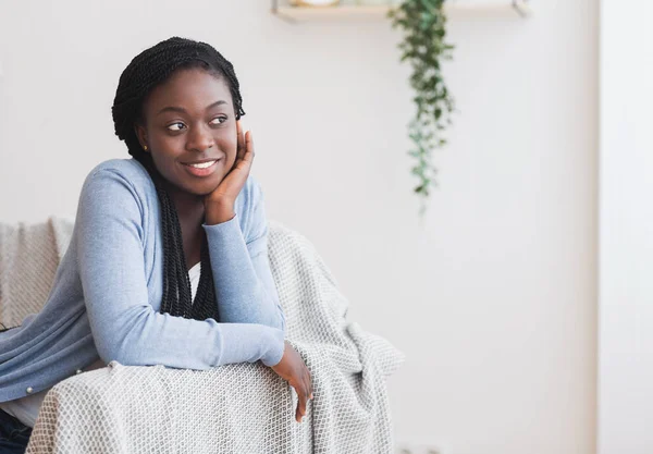 Retrato de chica negra sonriente tranquila descansando en el sofá en casa —  Fotos de Stock