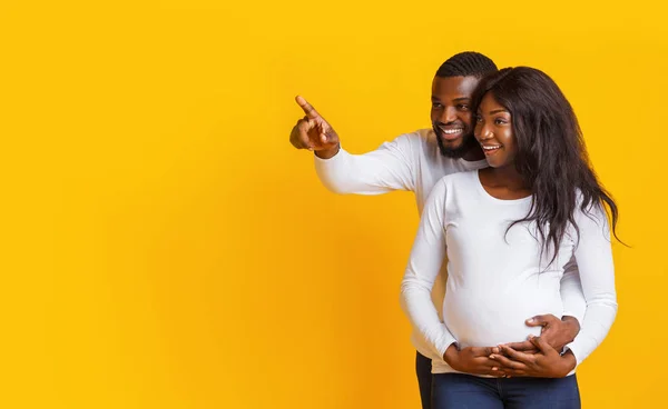 Возбужденный муж показывает беременной жене удивительные продажи — стоковое фото