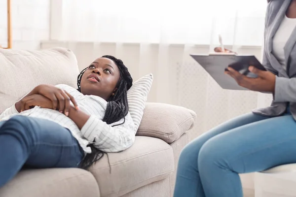 Deprimida joven mujer negra acostada en el sofá durante la sesión de psicoterapia — Foto de Stock