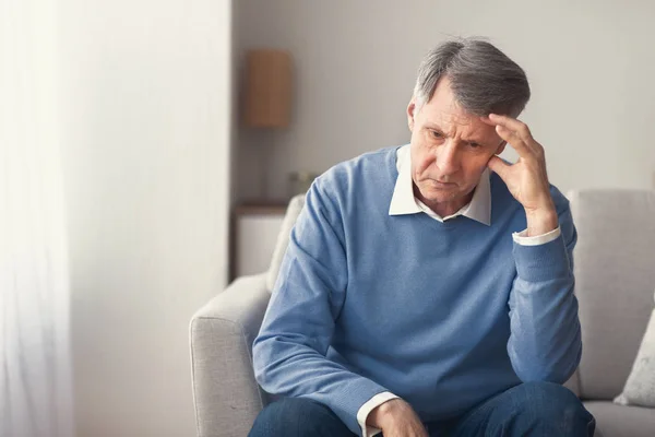 Nieszczęśliwy starszy mężczyzna myśli o emeryturze siedzi na kanapie — Zdjęcie stockowe