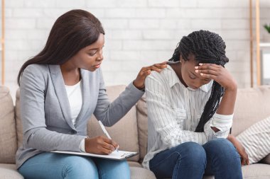Kadın psikolog, ofisteki kişisel muayenede depresyondaki kadını teselli ediyor.