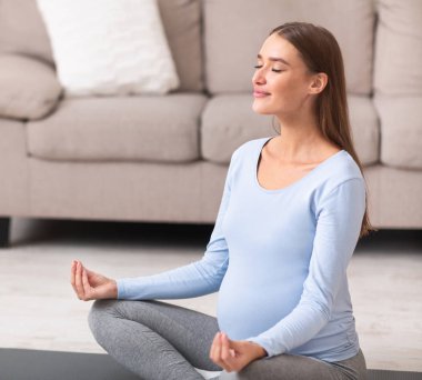 Evde yerde oturmuş meditasyon yapan rahat bir kız.