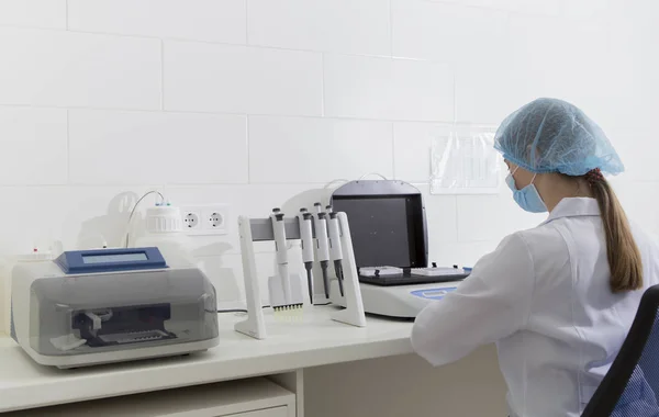 Asistente de laboratorio femenina que mira la máquina moderna para el análisis —  Fotos de Stock