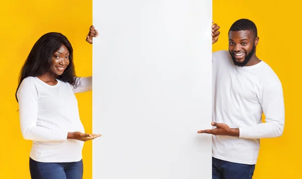 Sonriendo embarazada afro pareja mostrando vacío publicidad tablero —  Fotos de Stock