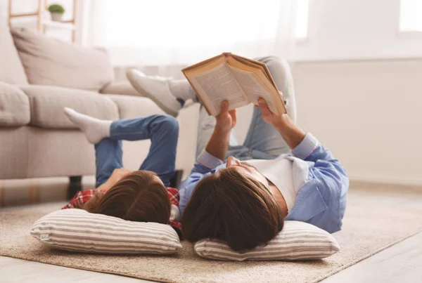 어린 소녀와 아버지는 바닥에 누워 책을 함께 즐기고 있다 — 스톡 사진