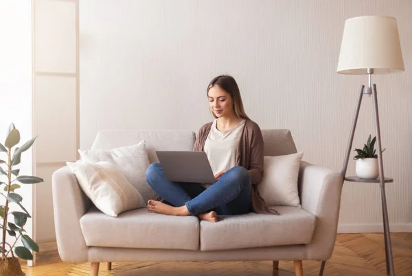 Söt ung flicka surfa på internet på laptop, vilar på soffan — Stockfoto