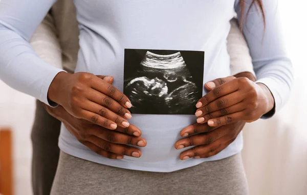 Black couple holding ultrasound image in front of woman belly — Stock Photo, Image