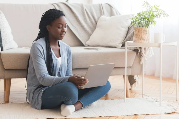 Afro ragazza seduta sul pavimento con il computer portatile, lavorando da casa — Foto Stock