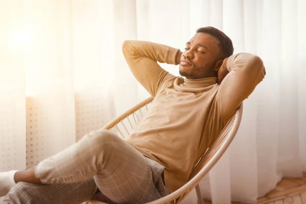 Fredlig svart man sitter på modern stol hemma — Stockfoto