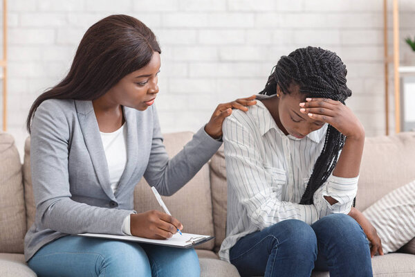 Женщина-психолог утешает депрессивную женщину на личной консультации в офисе

