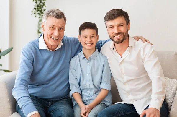 Хлопчик з батьком і дідусем сидить на дивані вдома — стокове фото