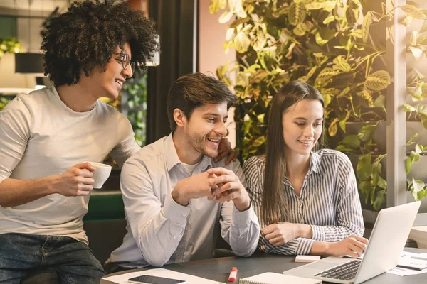 Partenaires millénaires lisant d'excellentes nouvelles sur ordinateur portable, manger dans un café — Photo