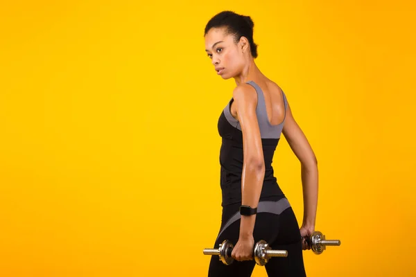 Determined Afro Girl Working Out With Dumbbells On Yellow Background — ストック写真