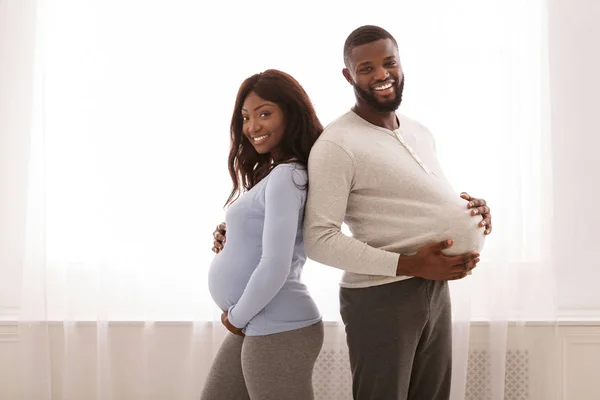 Casal grávida comparando o tamanho de sua barriga grande — Fotografia de Stock