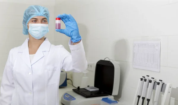 Assistente feminina alegre olhando para tubo de teste com amostra rosa — Fotografia de Stock