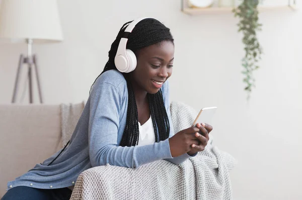 Sorridente Afro ragazza che indossa cuffie wireless, Ascoltare musica preferita su Smartphone — Foto Stock