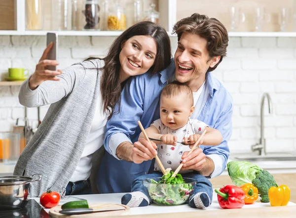 Anne, bebek ve kocasıyla mutfakta selfie çekiyor. — Stok fotoğraf