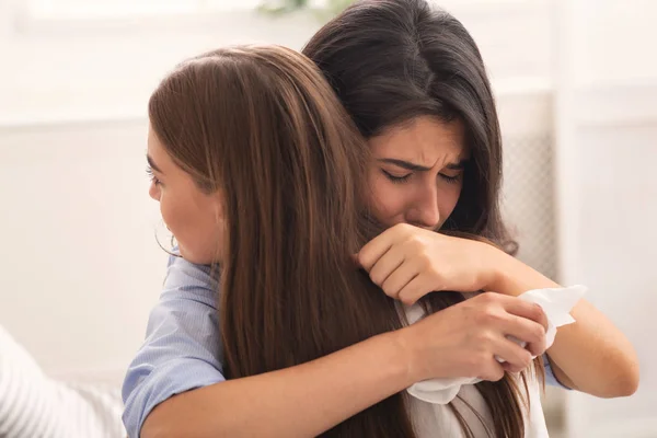 Mädchen weint und umarmt ihren mitfühlenden Freund, der auf der Couch im Haus sitzt — Stockfoto