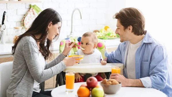 Glückliche Eltern füttern kleinen Sohn mit gesundem Haferbrei — Stockfoto