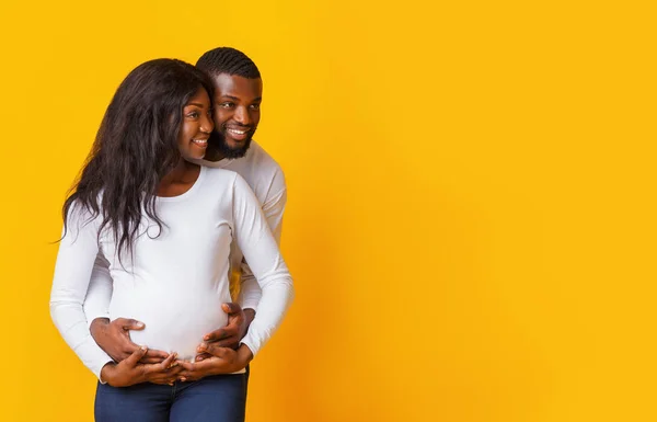Молодая беременная чёрная пара смотрит на пространство для копирования — стоковое фото