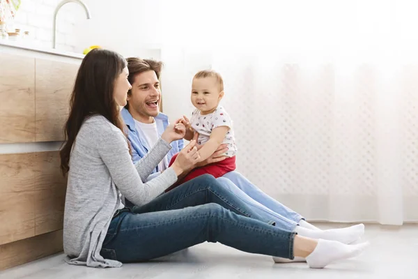 Millenniumi szülők játszanak a baba fia a konyha padlóján — Stock Fotó
