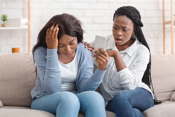 Deprimida mulher negra mostrando seu amigo Smartphone com má mensagem — Fotografia de Stock