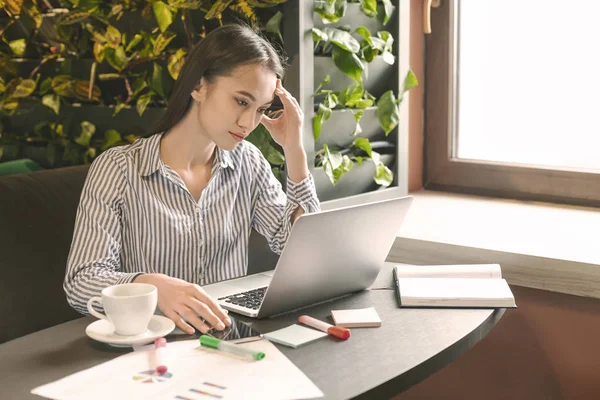 Donna d'affari stressata seduta ad analizzare i dati sul computer portatile nel caffè — Foto Stock