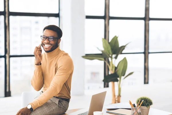 Negro hablando por teléfono sentado en la mesa —  Fotos de Stock