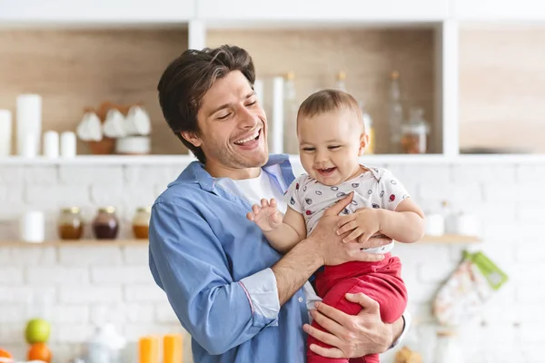 Papi alegre abrazando a su adorable bebé en la cocina — Foto de Stock