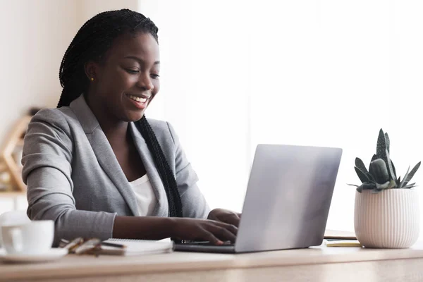 Μαύρη Millennial επιχειρηματίας χρησιμοποιώντας φορητό υπολογιστή στο σύγχρονο γραφείο — Φωτογραφία Αρχείου