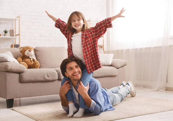 Menina feliz sentada nos ombros do pai com as mãos para cima — Fotografia de Stock