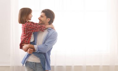 Yakışıklı baba tatlı kızını kucağında tutuyor, birbirine bakıyor.