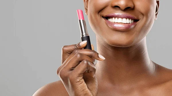 Hermosa afro chica sosteniendo lápiz labial rosa en la mano y sonriendo — Foto de Stock