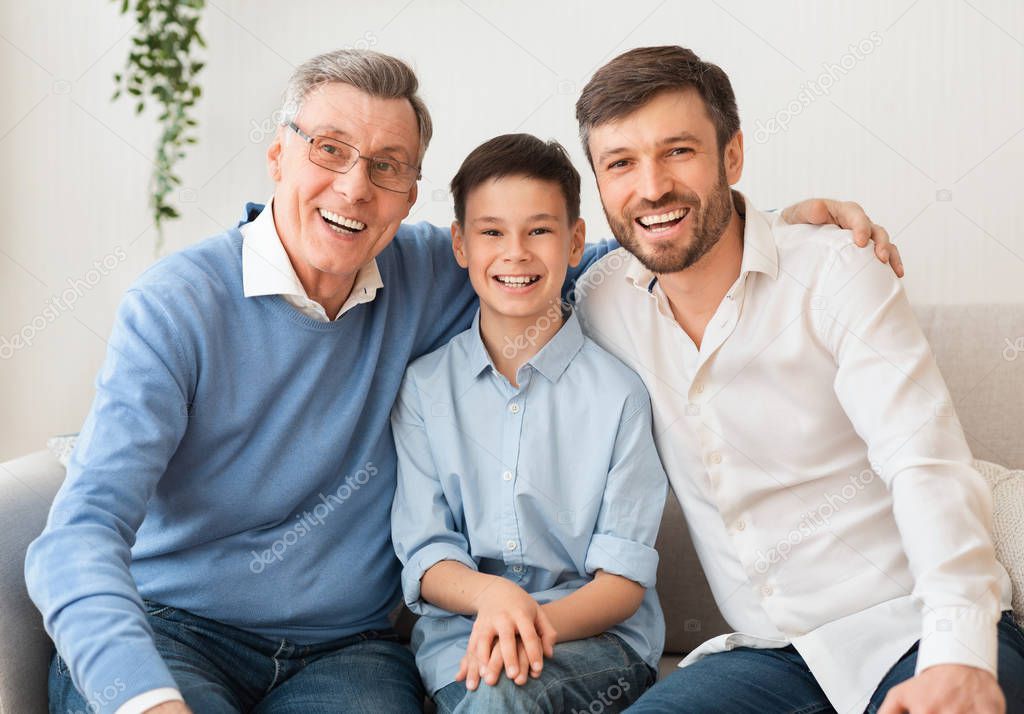 Grandpa With Mature Son And Grandson Sitting On Couch Indoor