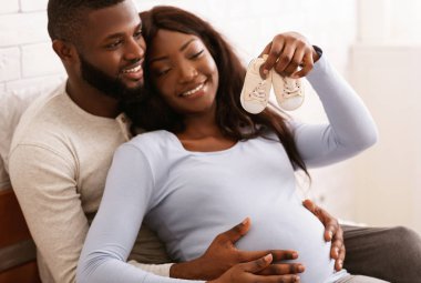 Hamile çift gelecekteki bebek çizmelerine bakıyor.