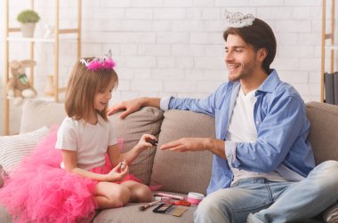 Küçük prenses babasının tırnaklarını parlatıyor.