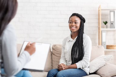 Happy black woman sitting at psychologist office after successful therapy clipart