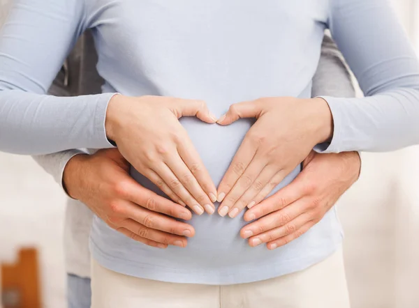 Casal amoroso fazendo forma de coração na barriga grávida com as mãos — Fotografia de Stock