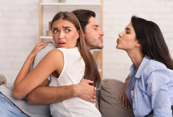 여자가 남자 친구를 껴안는 동안 남자 친구는 실내에 앉아 키스한다 — 스톡 사진