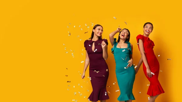 Trois modèles posant sous des confettis d'argent tombant, fond jaune, panorama — Photo