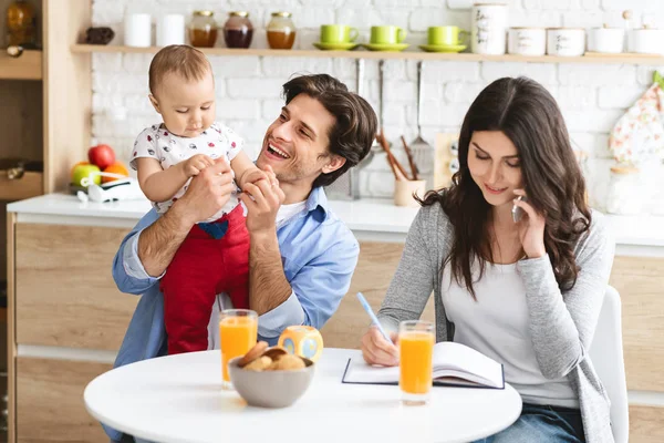 Papa spielt mit Baby, seine Frau telefoniert mit Partnern — Stockfoto