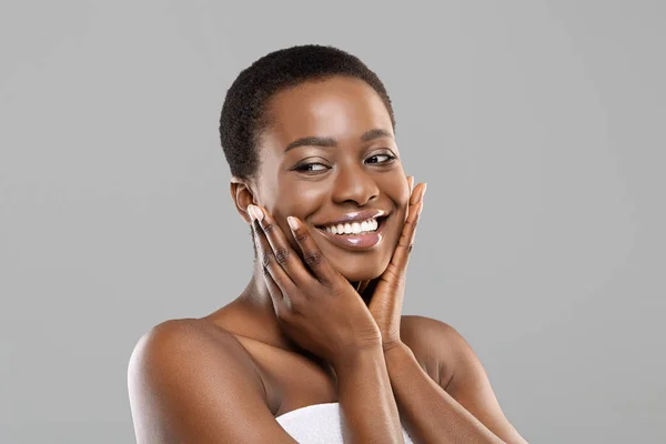 Привлекательная черная девушка касается своей гладкой кожи на щеках — стоковое фото
