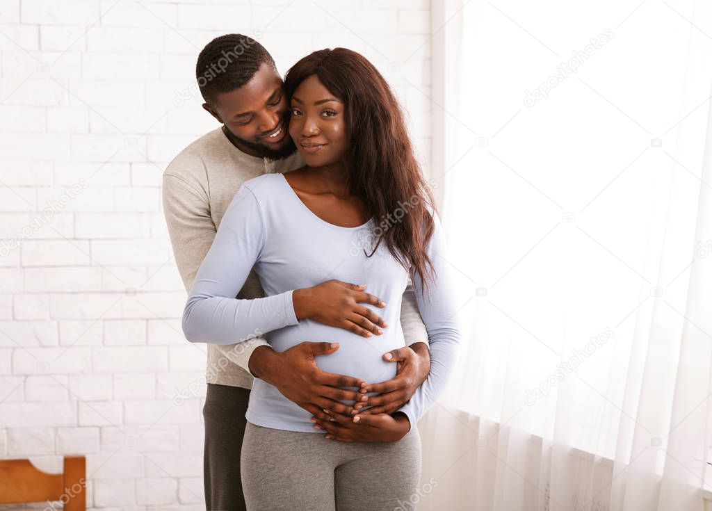 African husband embracing his pregnant wife at home