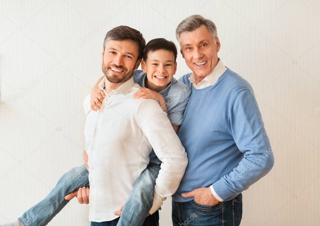 Man With Son And Senior Father Posing Near White Wall