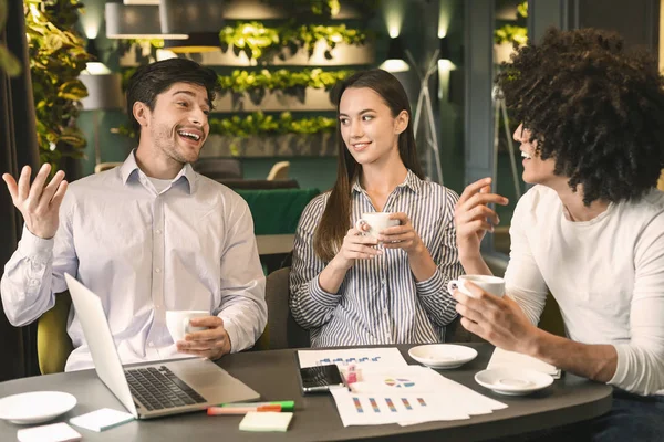 Socios amigables discutiendo el proyecto y disfrutando del café en la cafetería —  Fotos de Stock