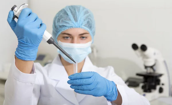 Cientista feminina soltando amostras de pipeta grande para testes em equipamentos de laboratório modernos — Fotografia de Stock